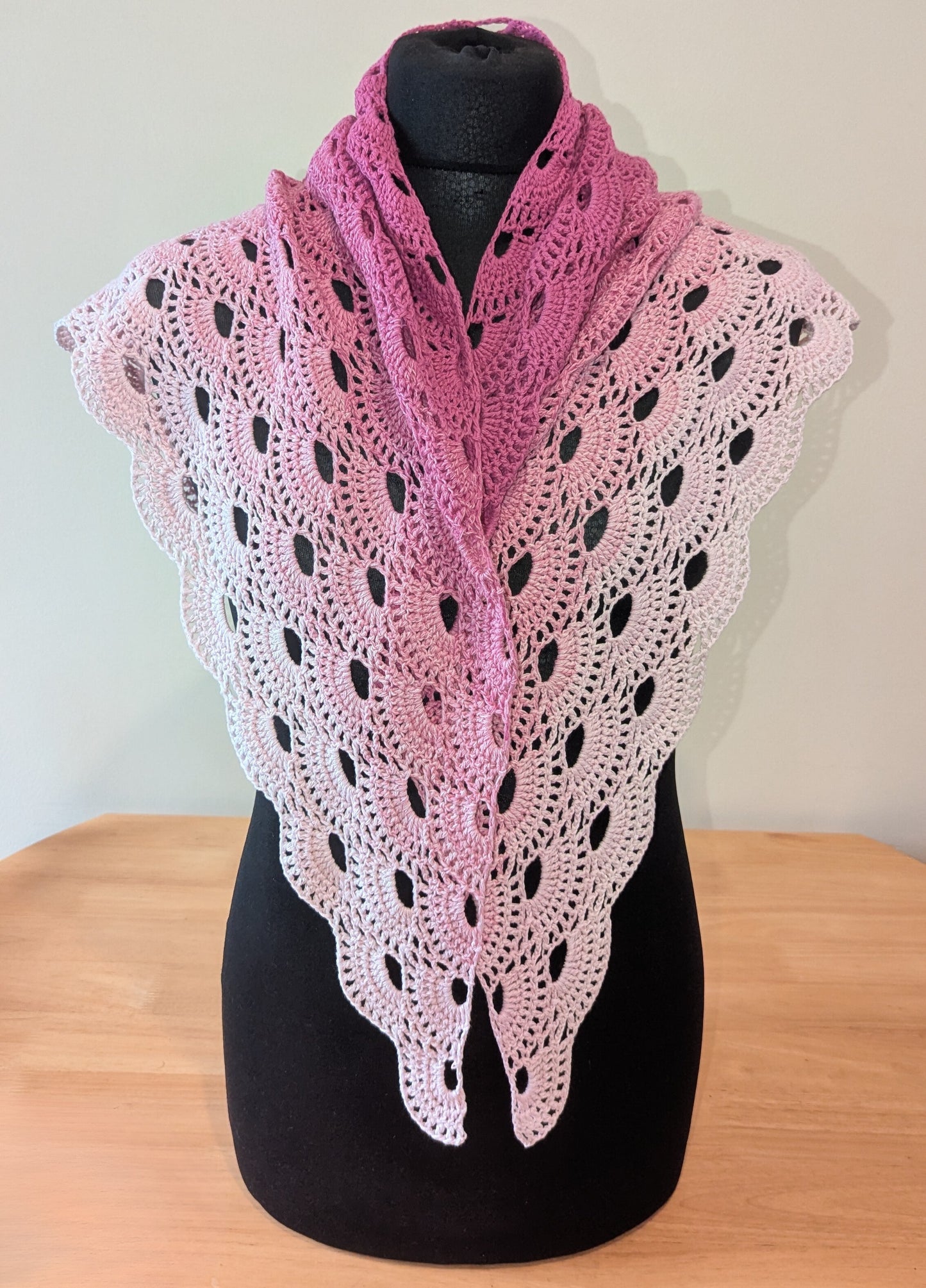 Pink and white shawl on a black mannequin against a white background
