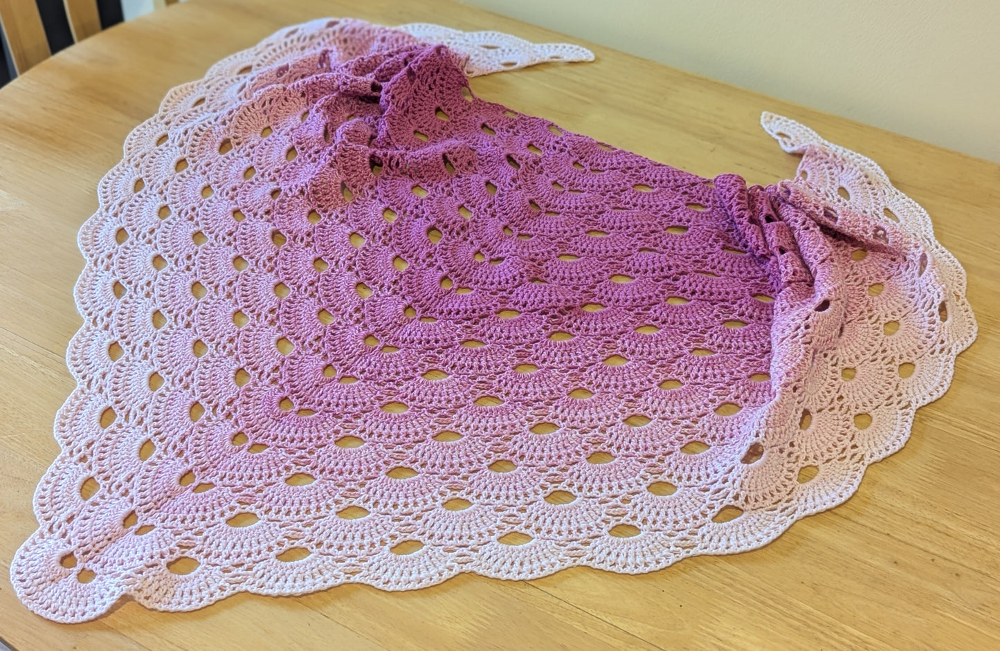 Pink crocheted shawl on a wooden surface
