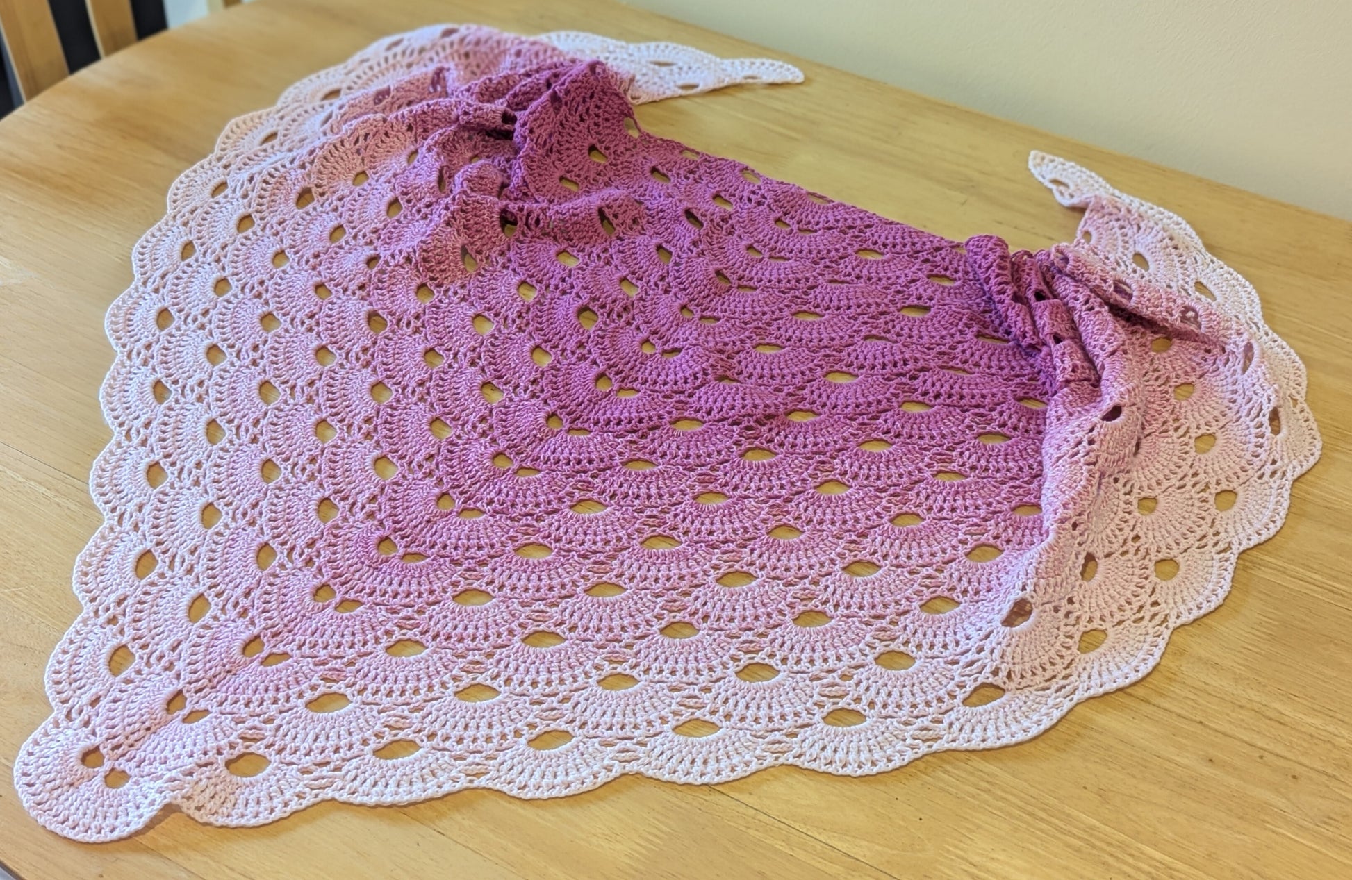 Pink crocheted shawl on a wooden surface