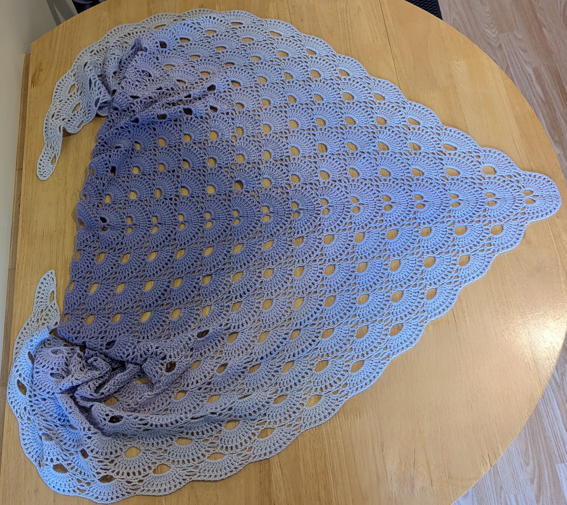 Purple crocheted shawl on a wooden surface