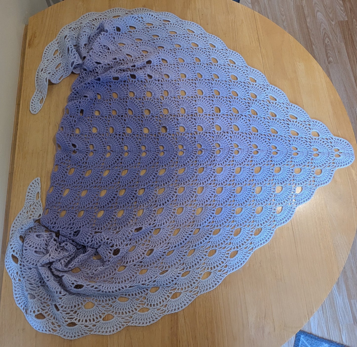 Purple crocheted shawl on a wooden surface