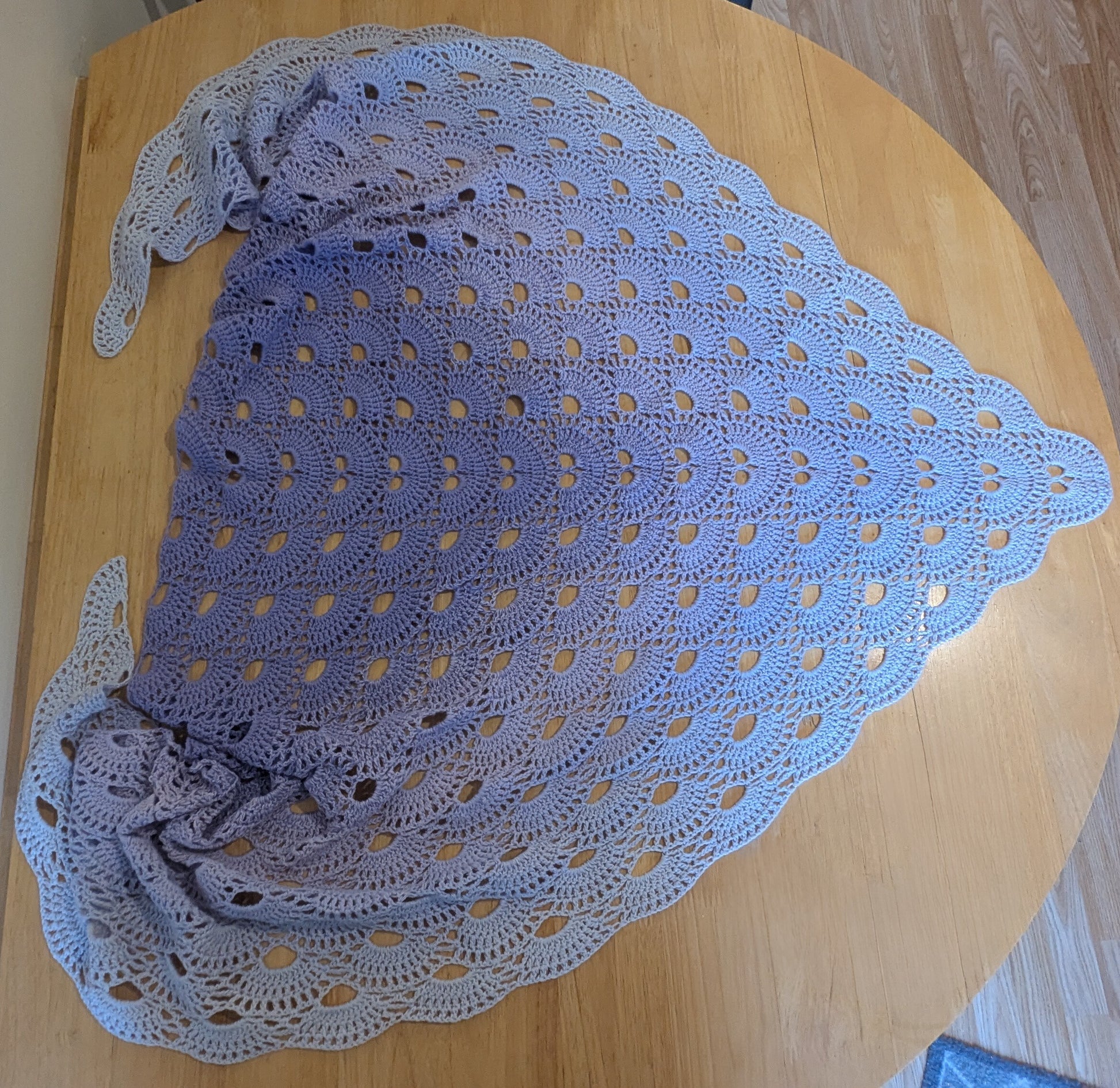 Purple crocheted shawl on a wooden surface