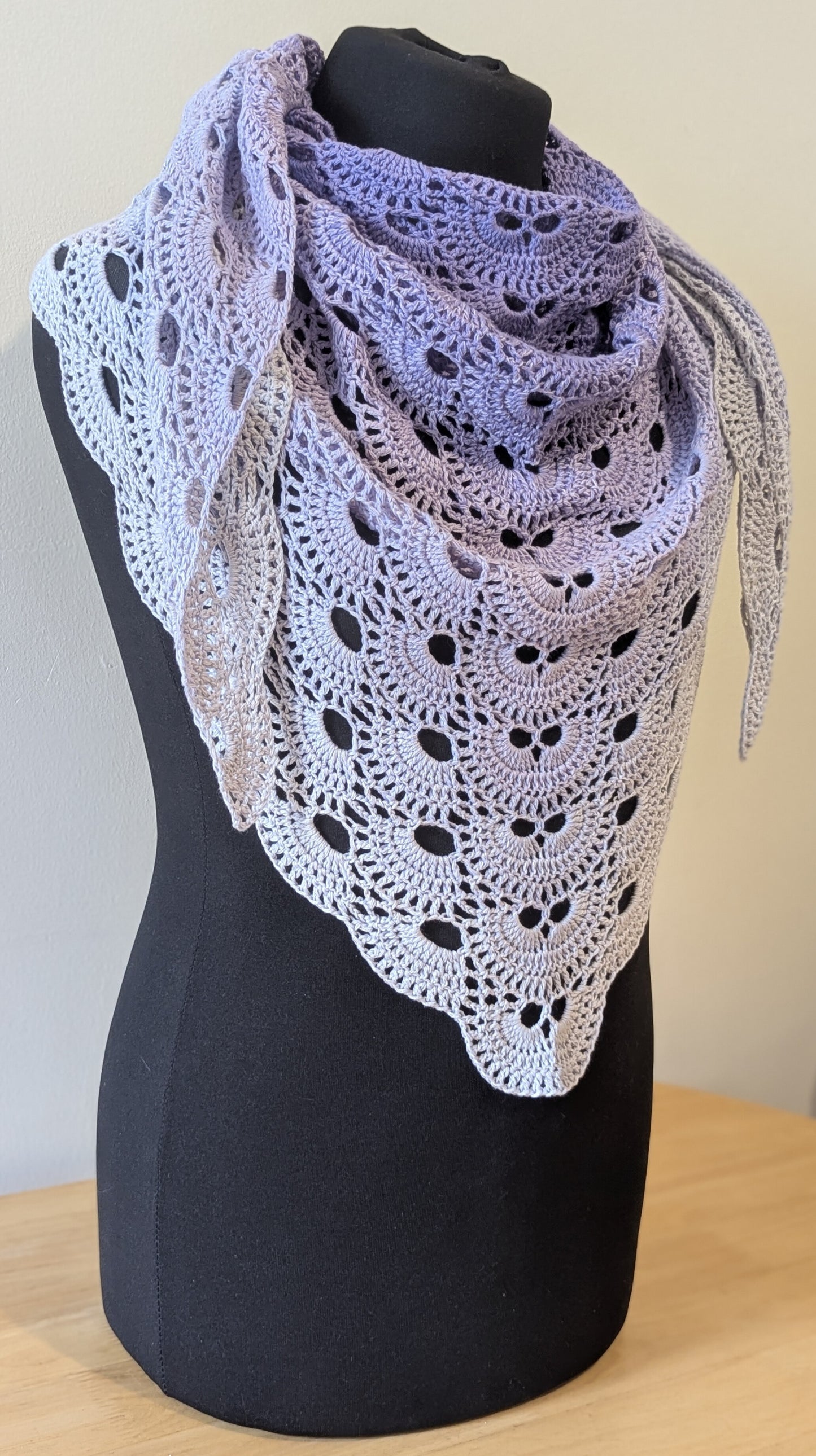 Lace shawl draped over a black mannequin against a plain background