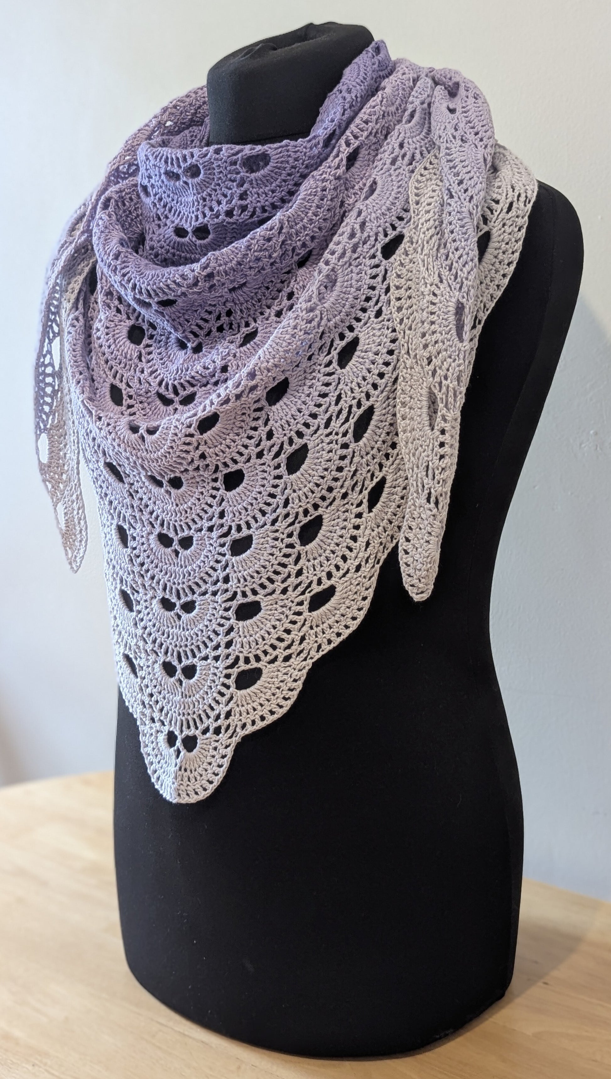 Lace purple shawl on a black mannequin against a white background