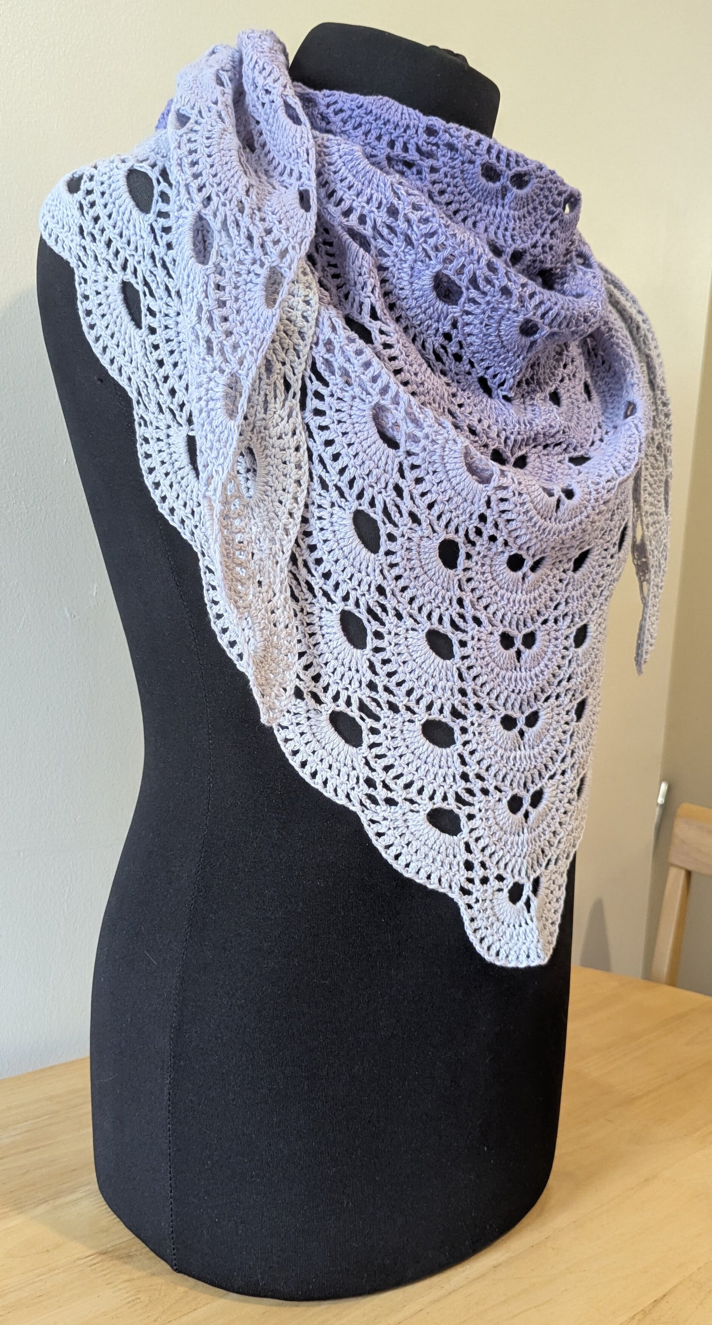 Crocheted shawl draped over a mannequin against a plain background