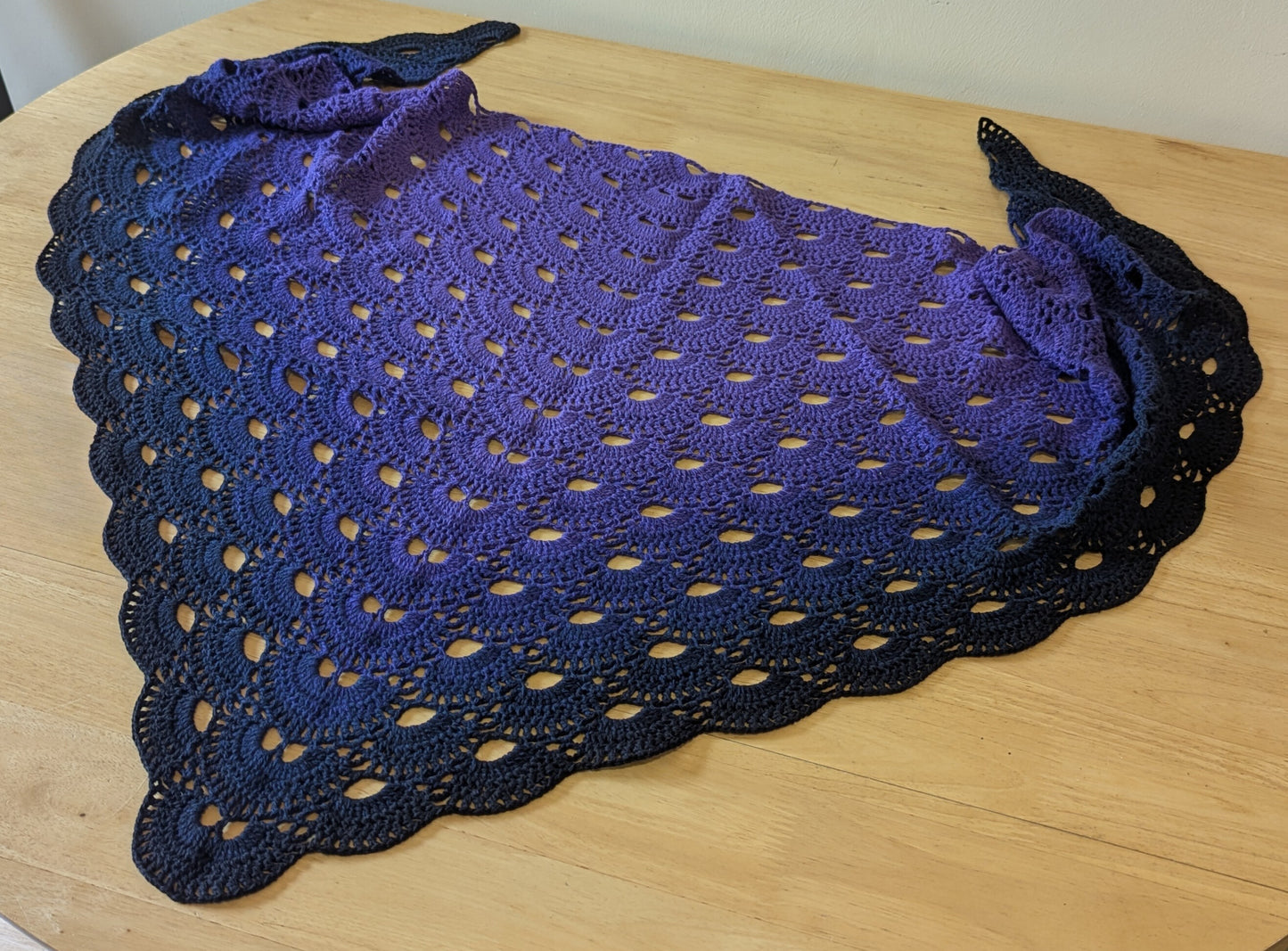 Purple crocheted shawl on a wooden surface
