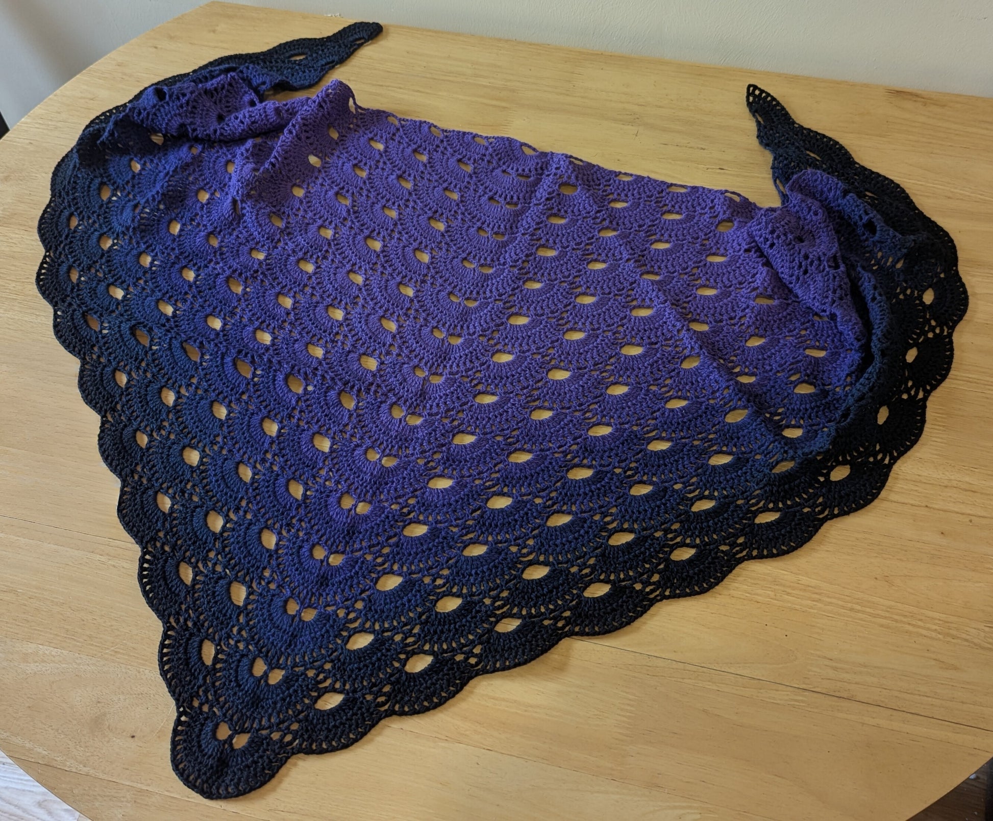 Purple crocheted shawl on a wooden surface