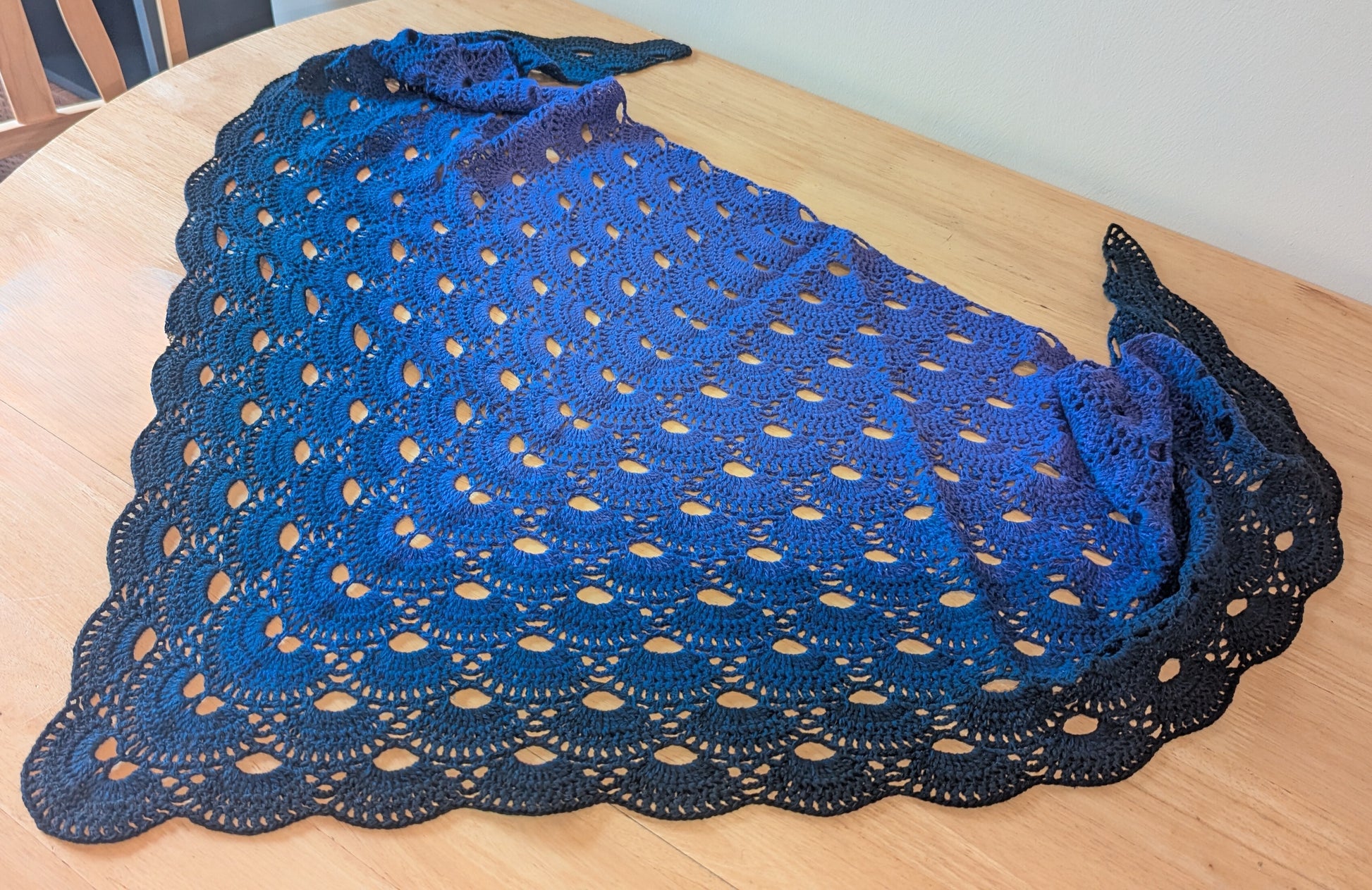 Purple crocheted shawl on a wooden surface