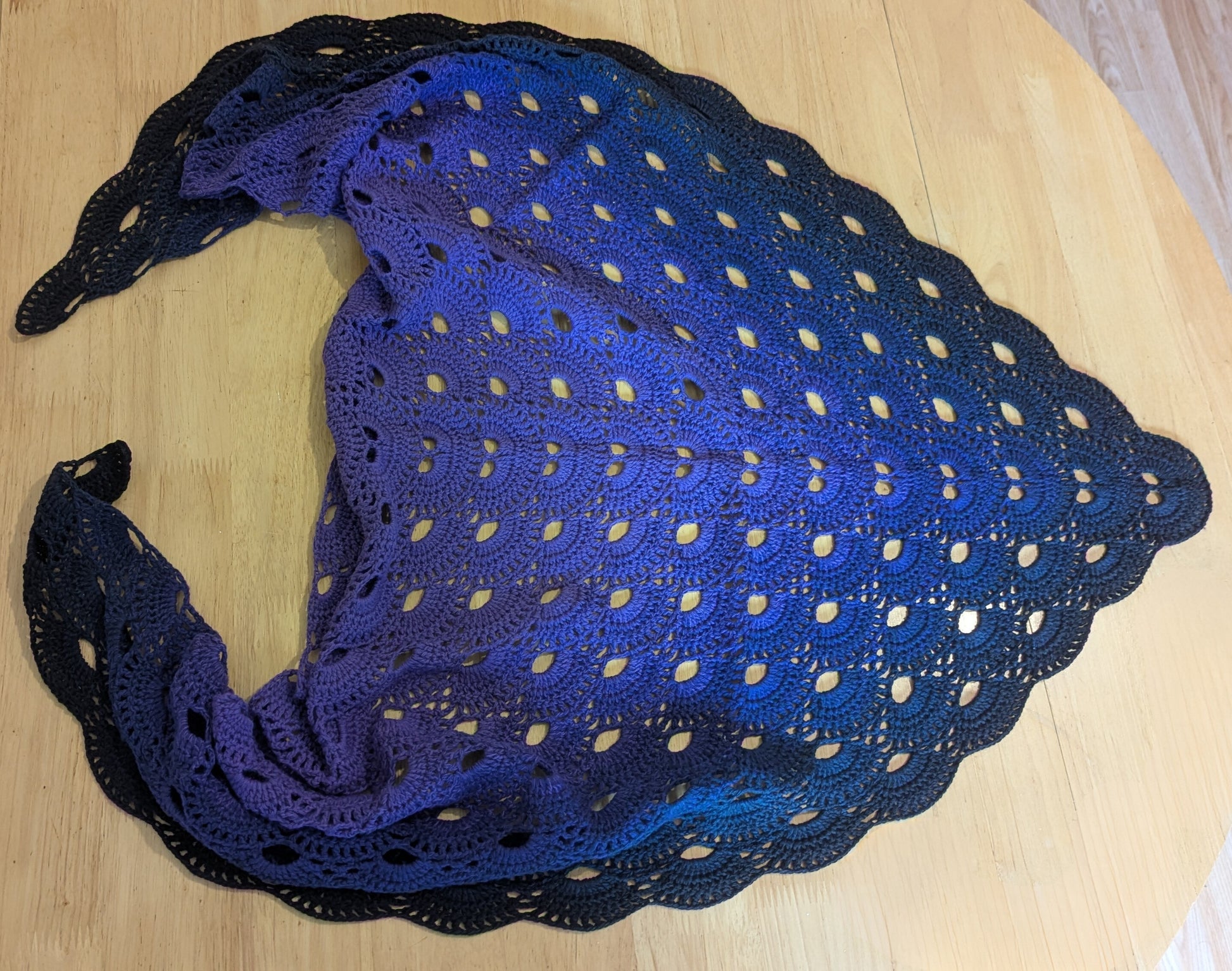 Purple and black crocheted shawl on a wooden surface