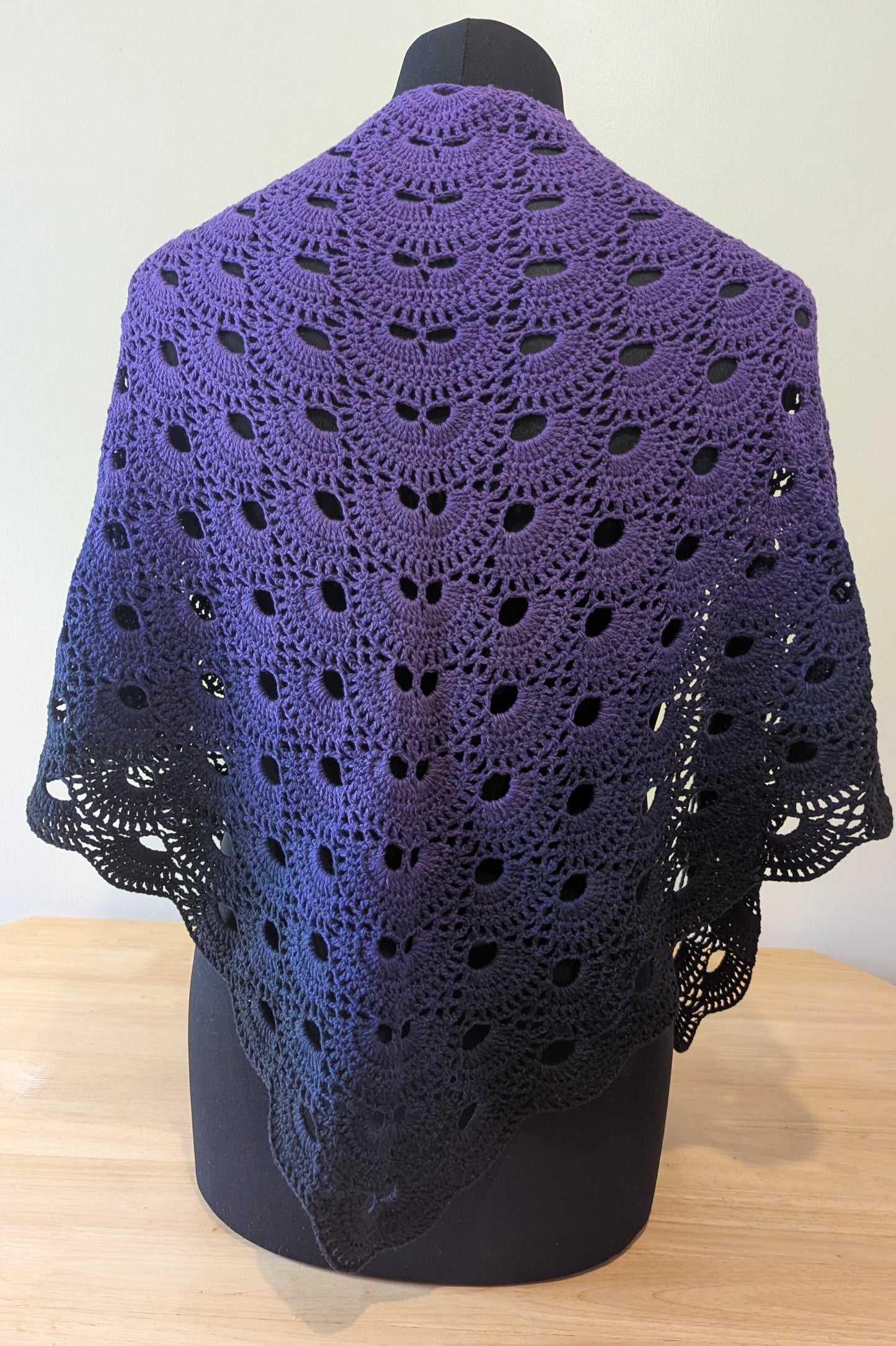 Purple crocheted shawl on a mannequin against a white background