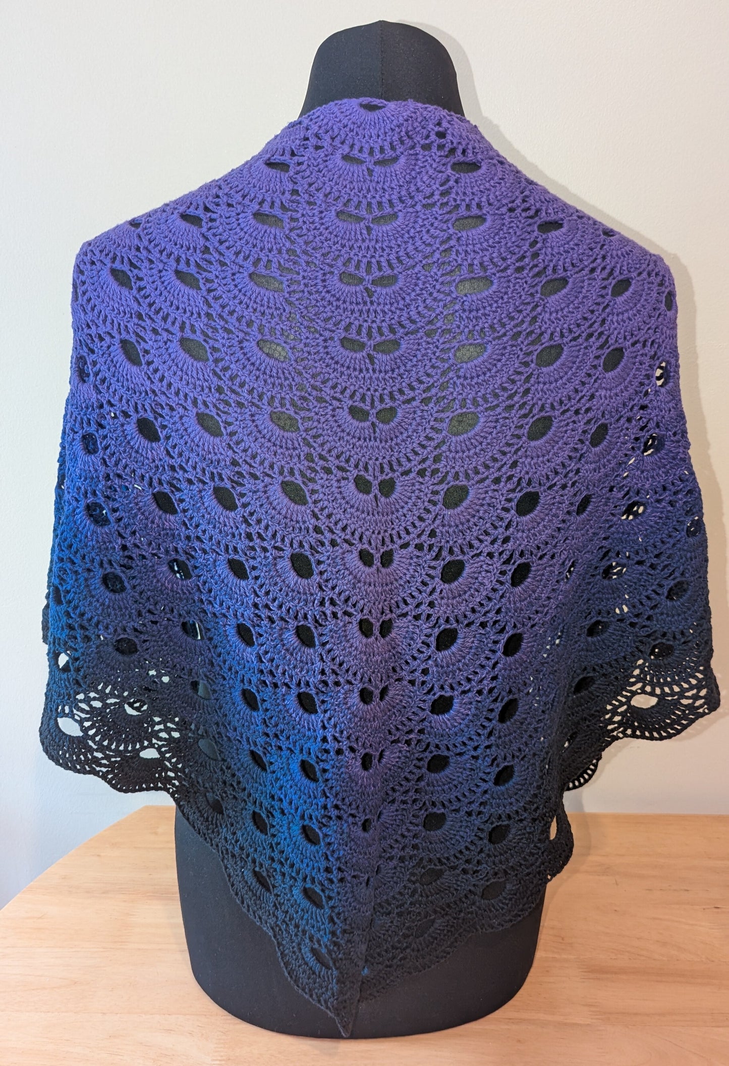Purple crocheted shawl on a mannequin against a white background