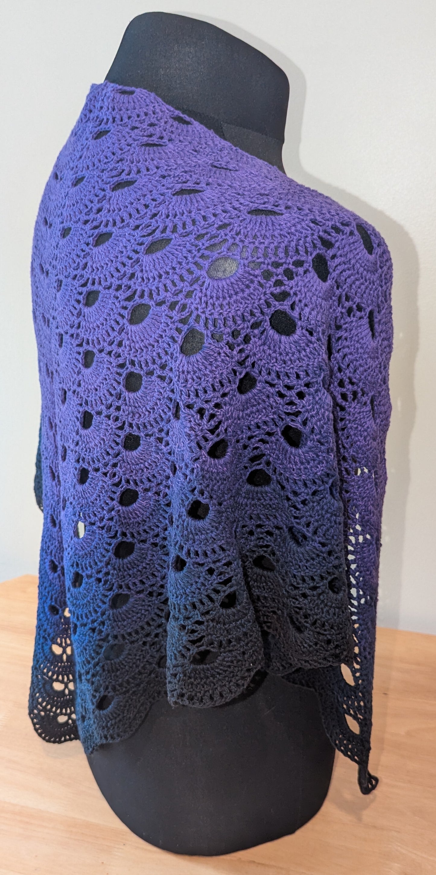 Purple crochet shawl on a mannequin against a white background