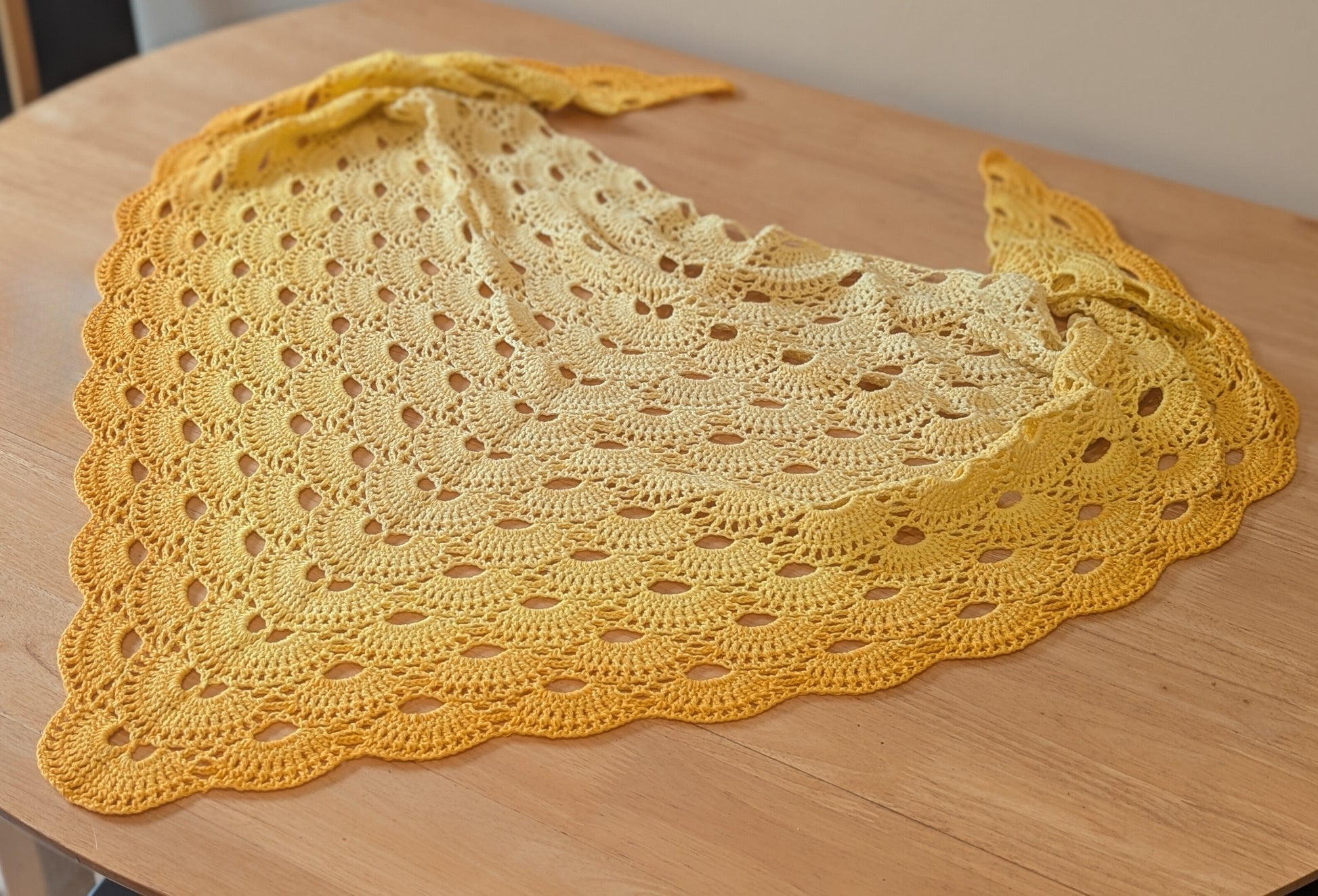 Yellow crochet shawl on a wooden surface