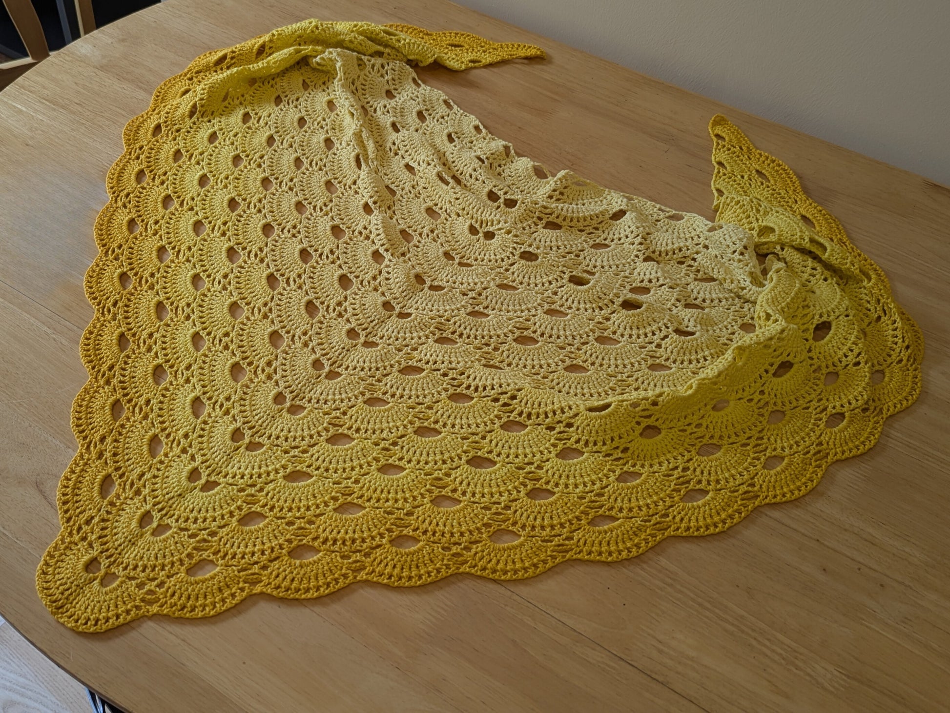 Yellow crocheted shawl on a wooden surface