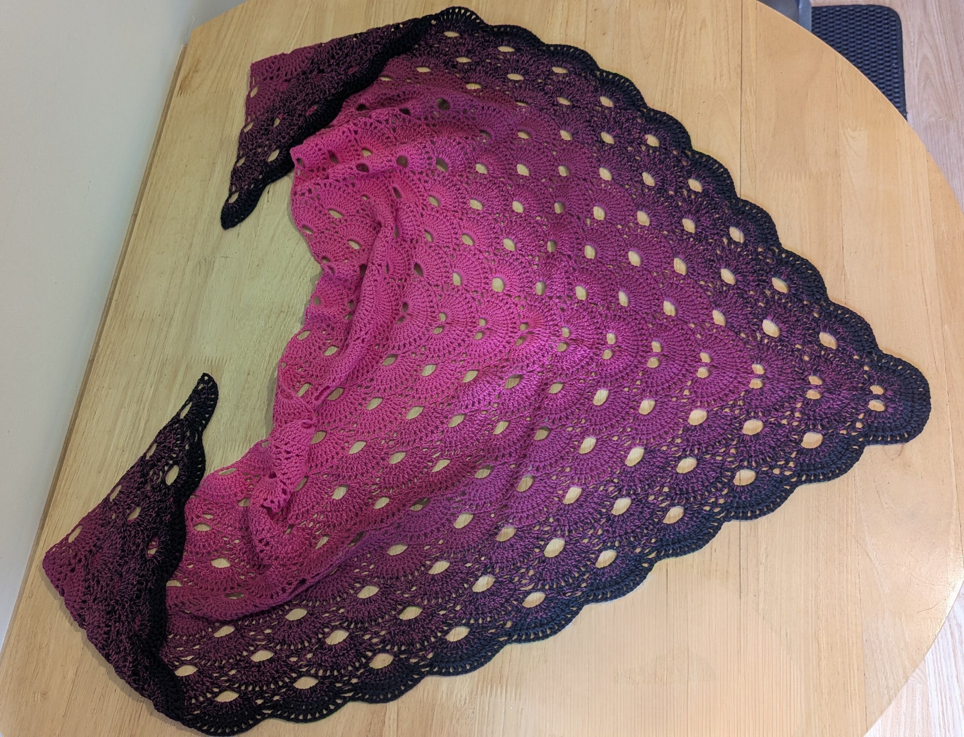 Pink and black gradient lace shawl on a wooden surface