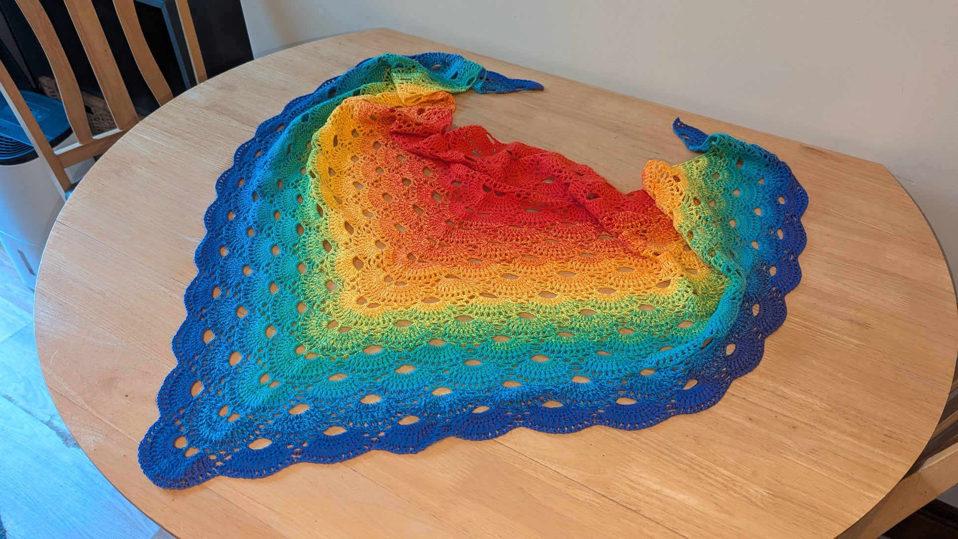 Colourful crocheted shawl on a wooden table