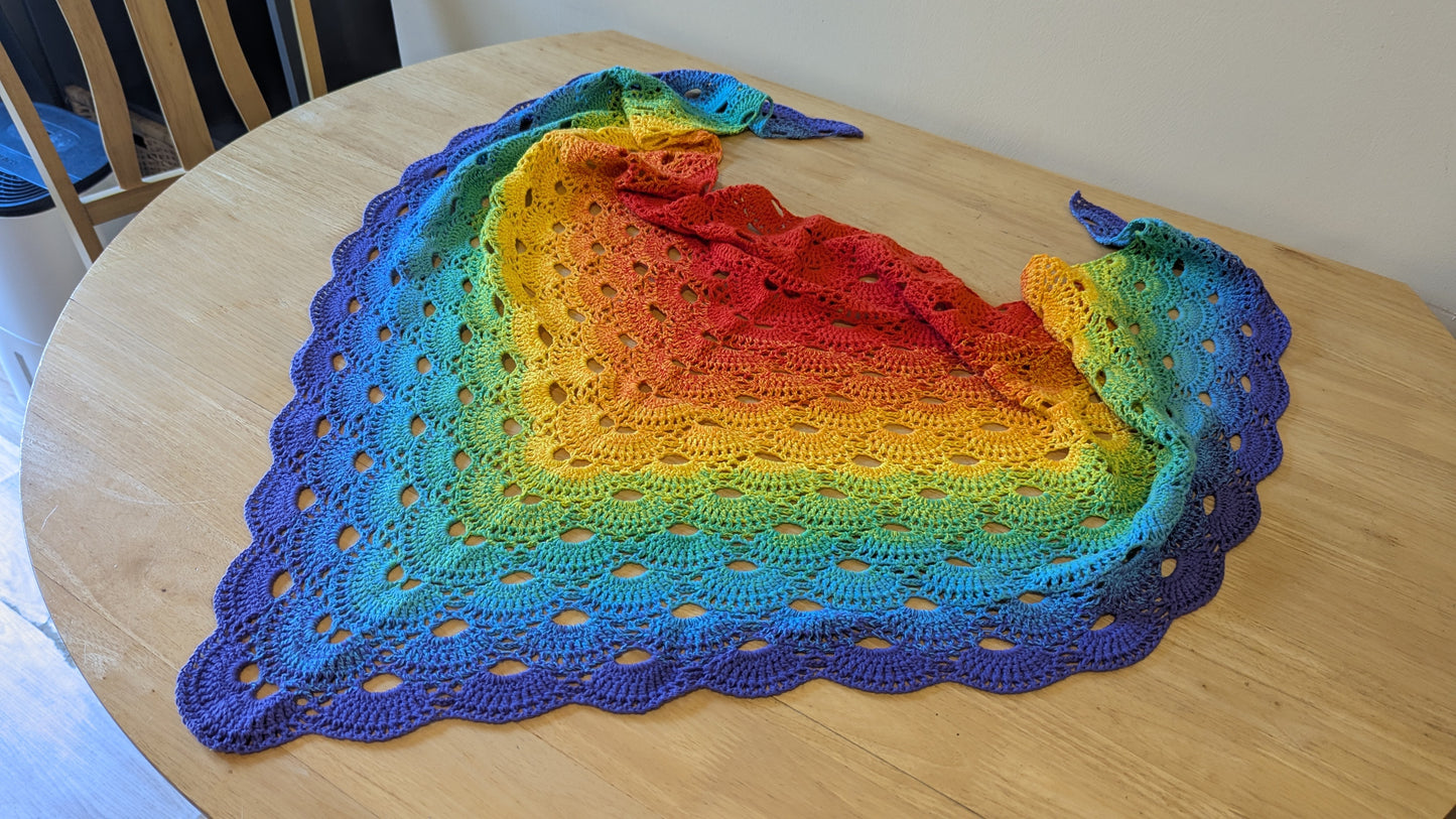 Colorful crocheted shawl on a wooden table