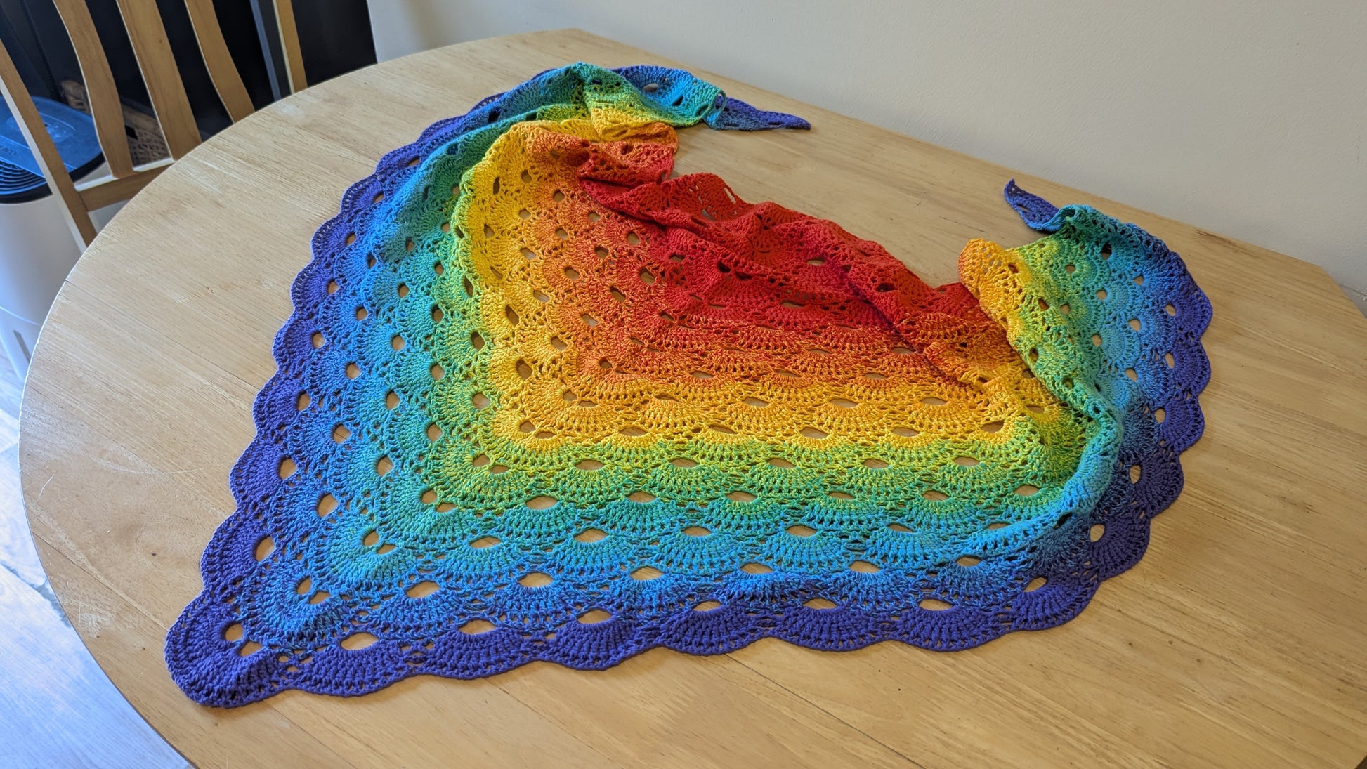 Colorful crocheted shawl on a wooden table