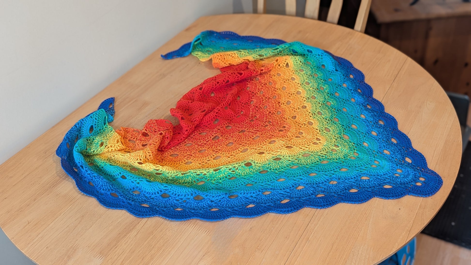 Colourful rainbow gradient crochet shawl on a wooden table