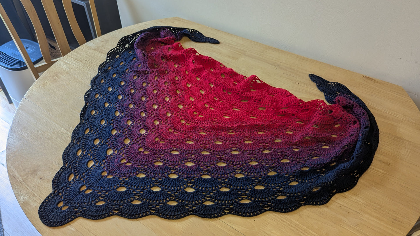 Crocheted shawl with gradient color pattern on a wooden table