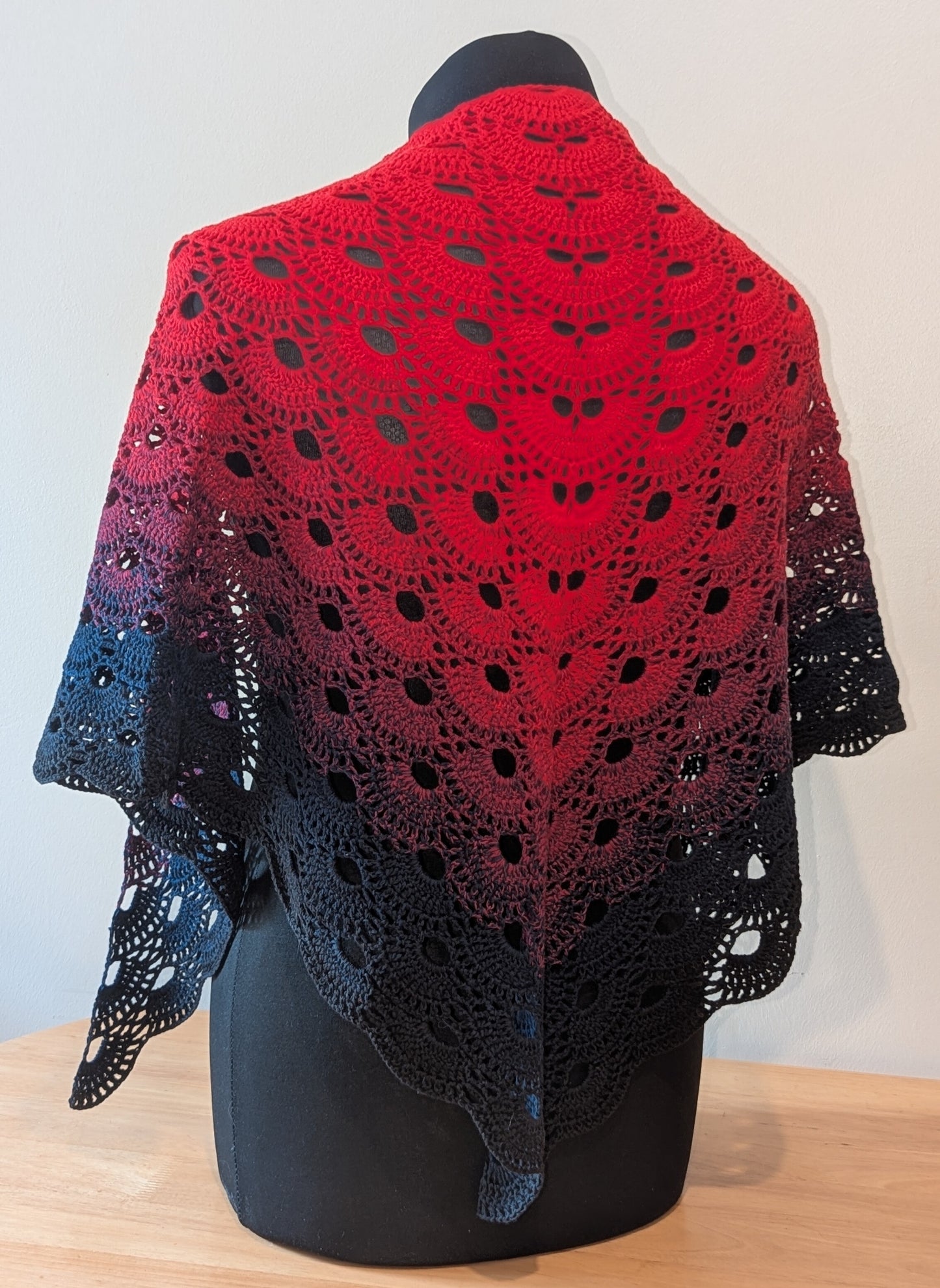 Red and black shawl on a mannequin against a white background