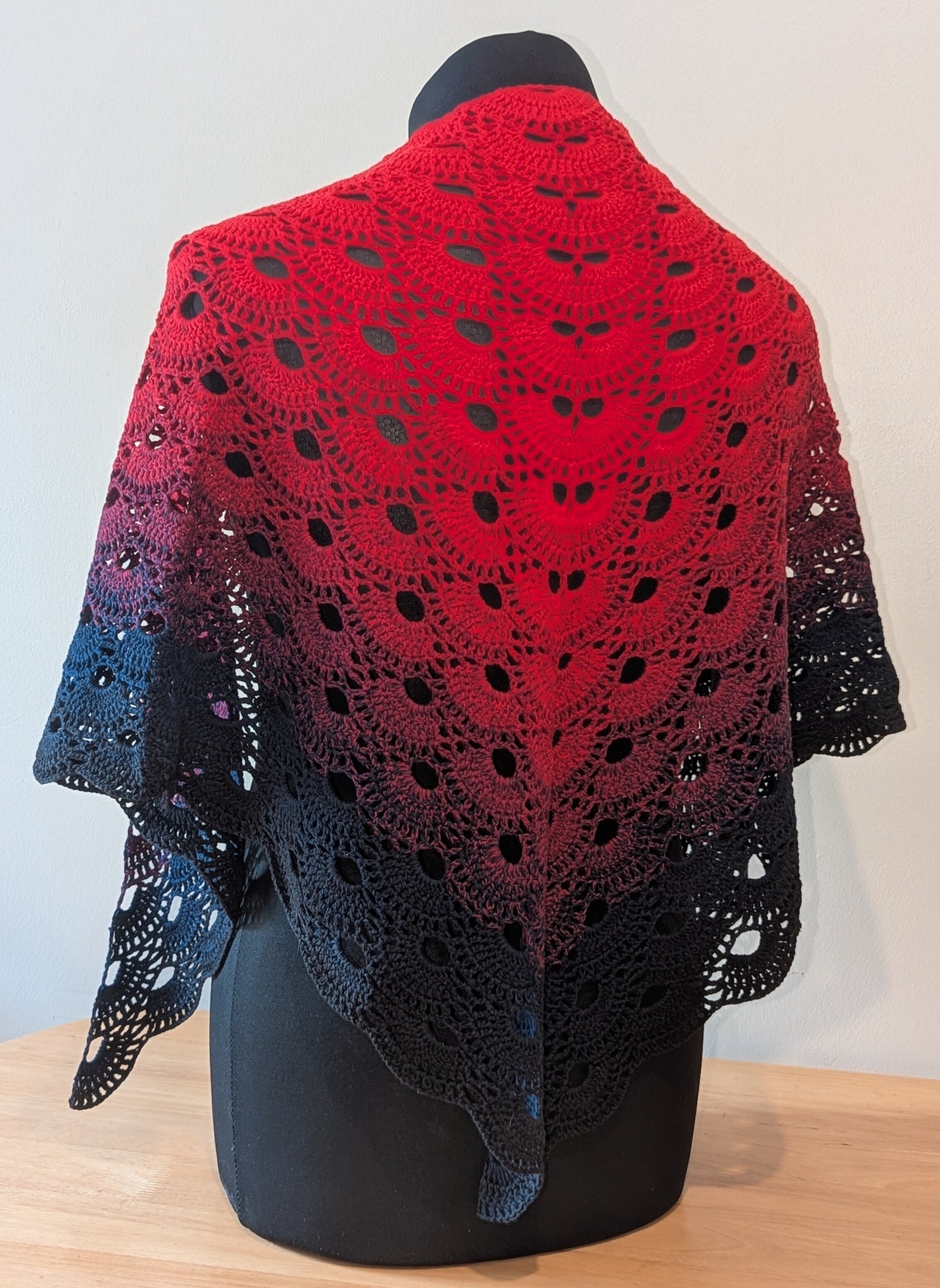 Red and black shawl on a mannequin against a white background