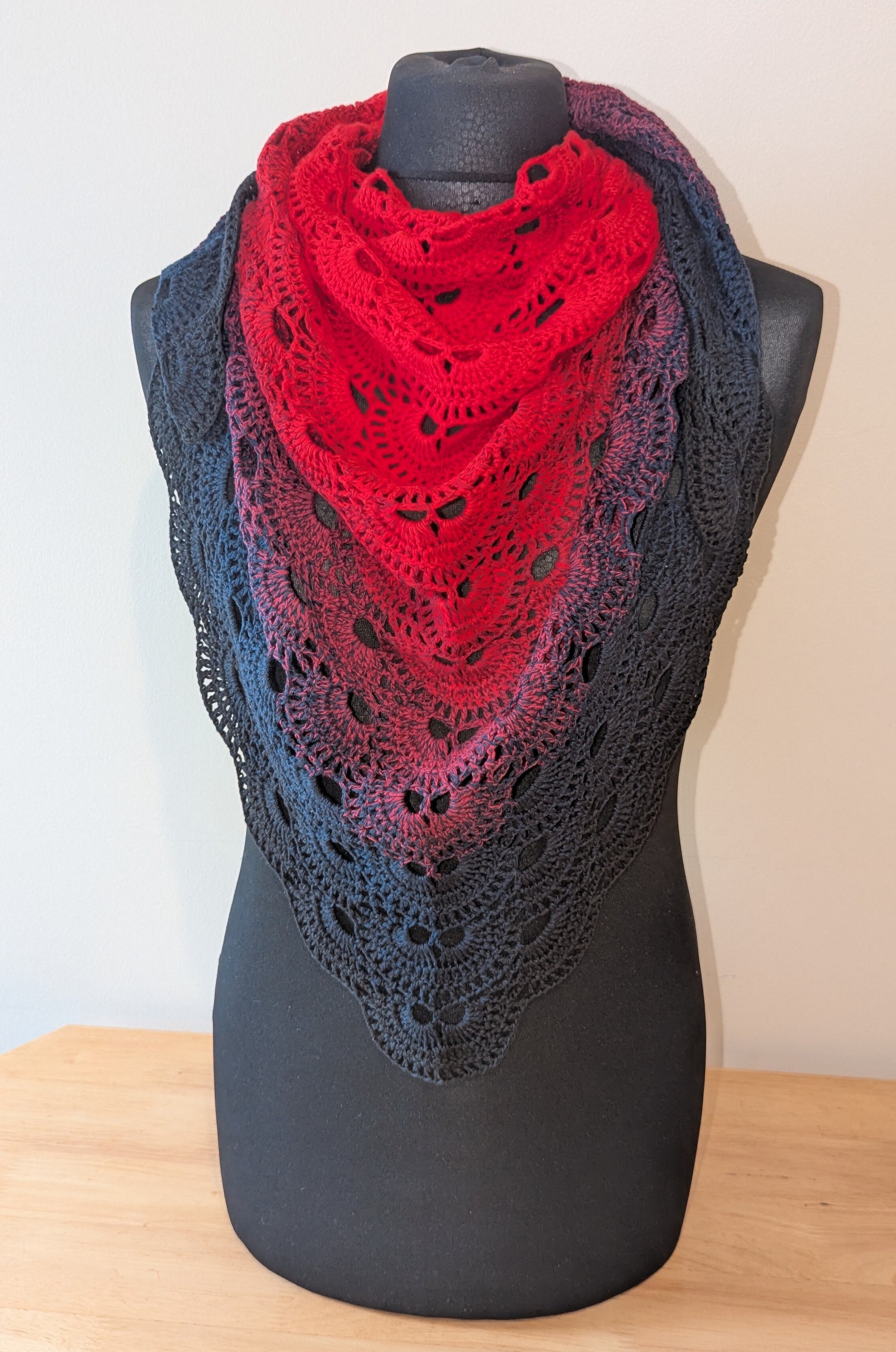Red and black gradient lace shawl on a black mannequin against a white background