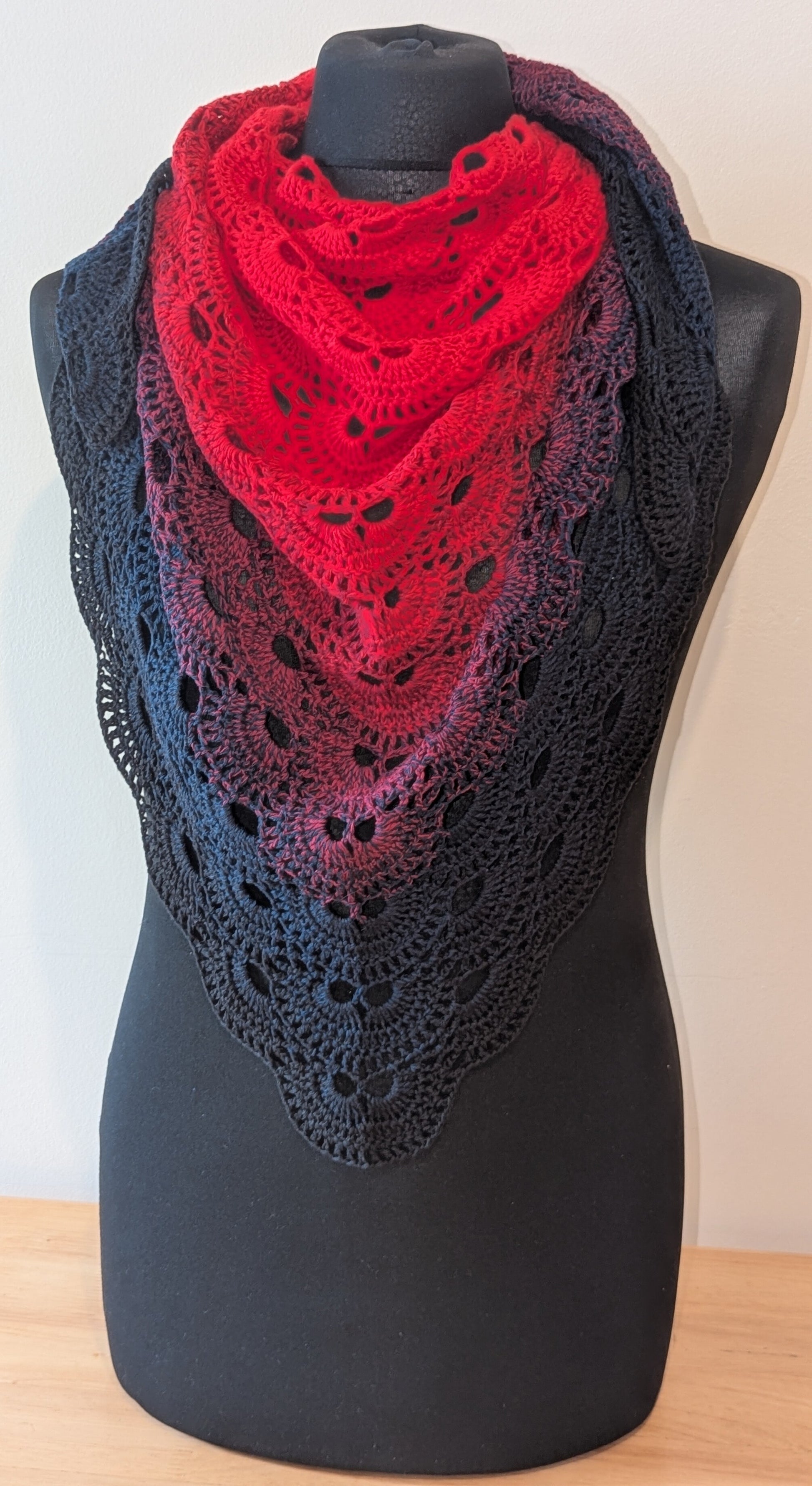 Red and black lace shawl on a mannequin against a white background