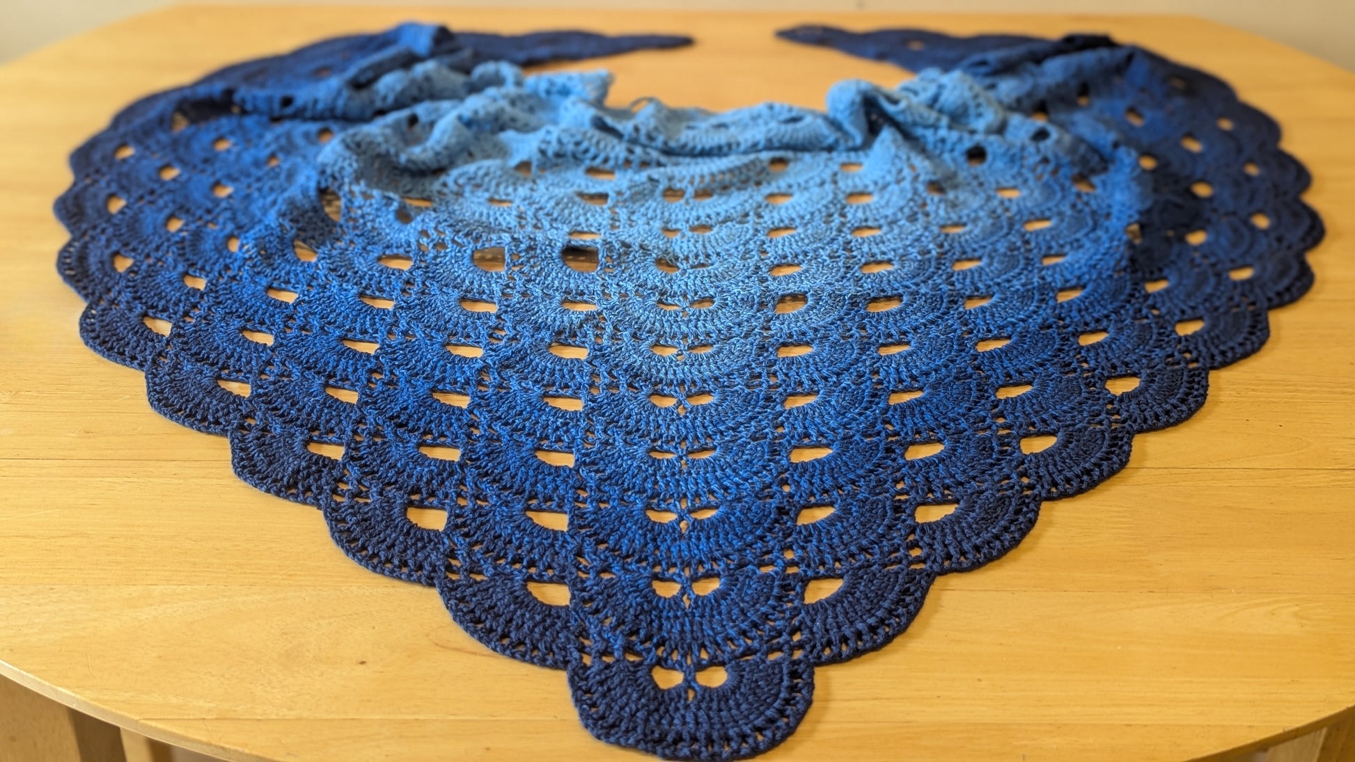 Blue crocheted shawl on a wooden surface