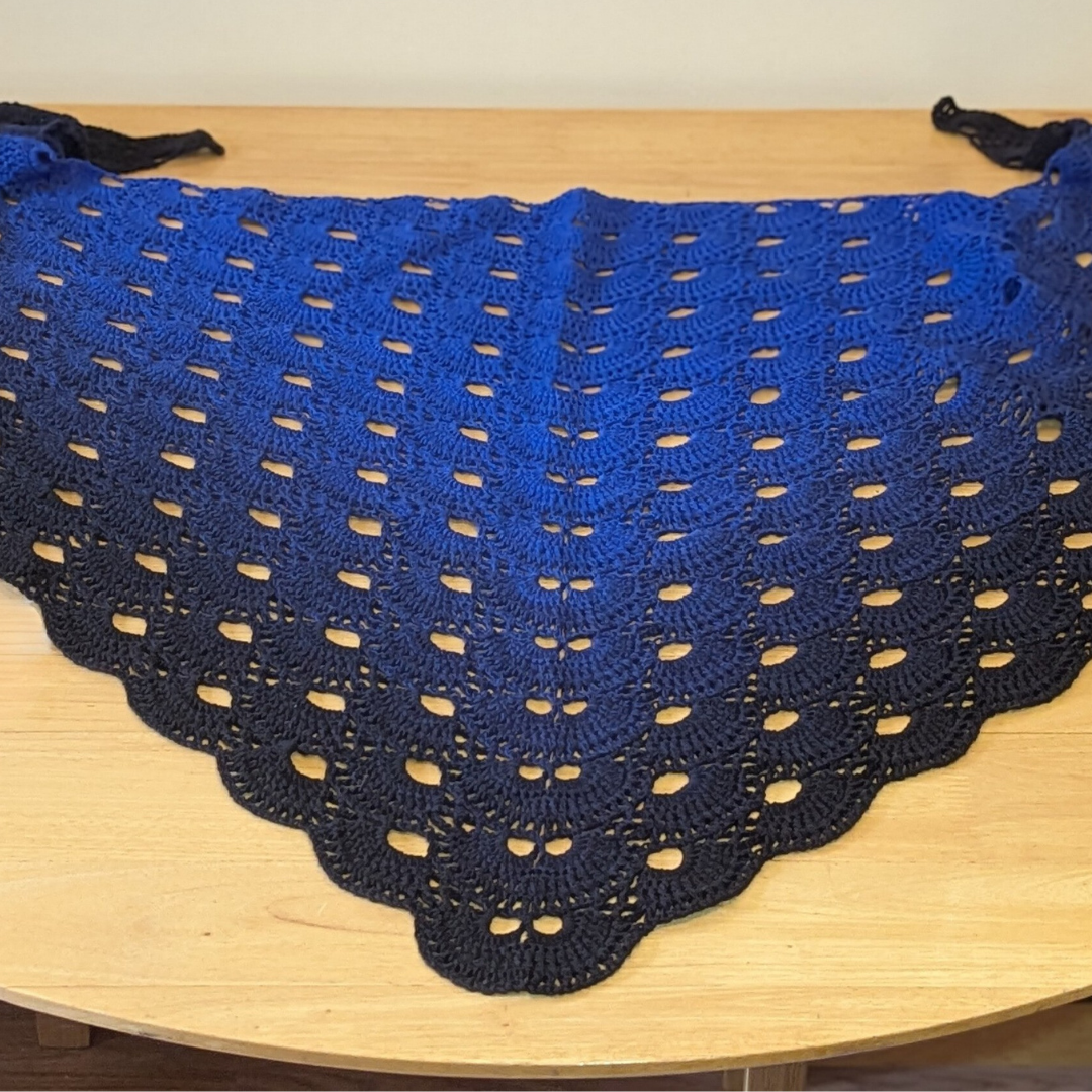 Blue and black crocheted shawl on a wooden surface