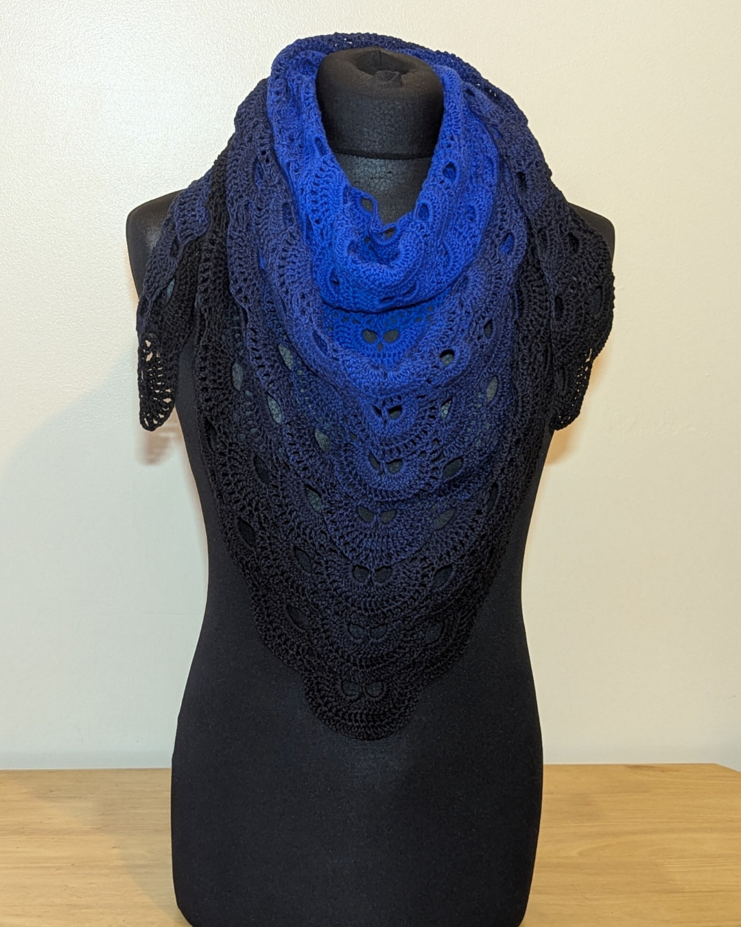 Blue and black lace shawl on a mannequin against a white background