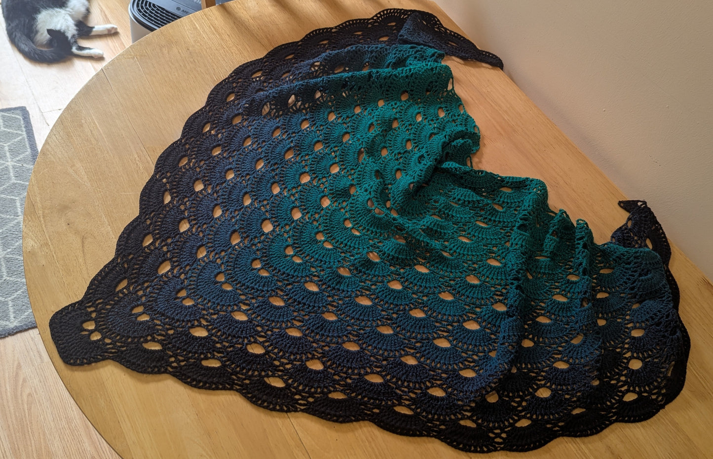 Crocheted green and black shawl on a wooden surface
